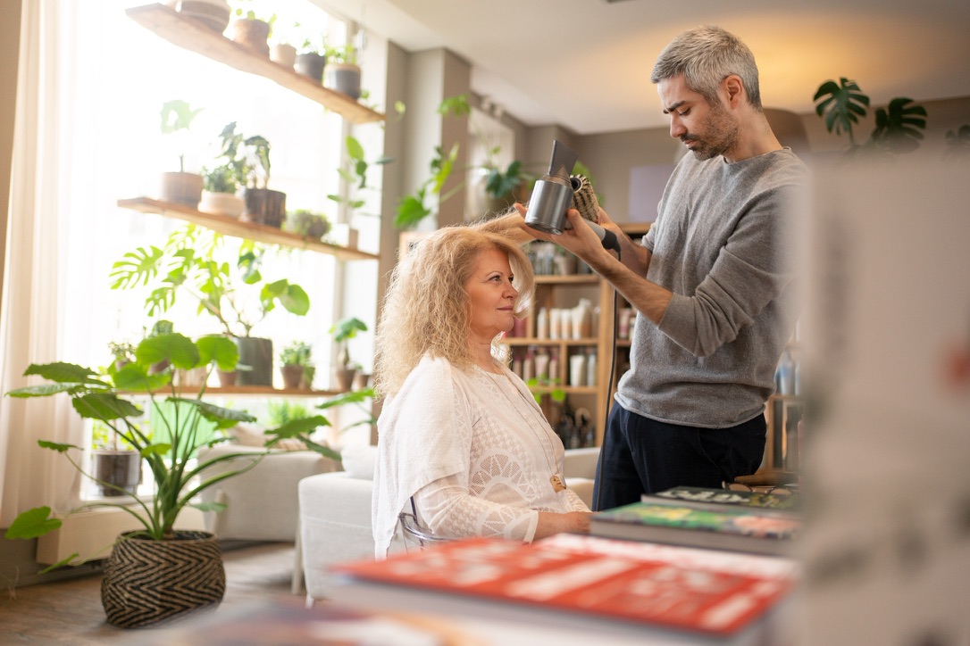 A stylist blow-drying a guest’s hair in the plant-filled HairSpa By Jeremy salon
